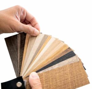 Eine Hand hält ein aufgefächertes Set von Holzfußbodenmustern in verschiedenen Farbtönen und Strukturen vor einem weißen Hintergrund, perfekt für die Inspiration Ihrer nächsten Einrichtungsplanung oder Ihres nächsten Interior Design Projekts mit Möbel Braum.