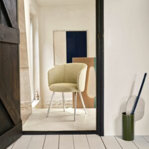 Ein moderner gelber Stuhl mit Metallbeinen steht im Mittelpunkt eines minimalistischen Raums, der durch eine offene Tür zu sehen ist; abstrakte Kunst und ein grüner Besenhalter fügen Winter Harmonie zu Hause hinzu und erinnern an die gemütliche Inspiration von Vitra Homestories.