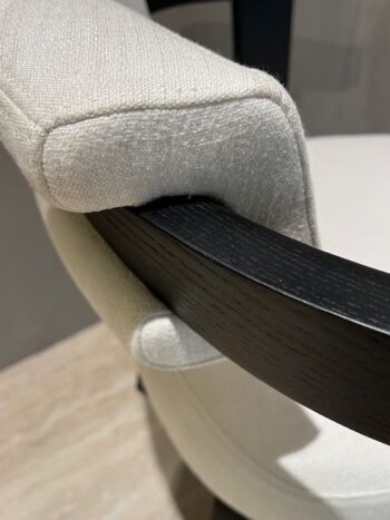 Nahaufnahme eines hell gepolsterten Molteni&C Porta Volta Stuhles mit einer dunklen Holzarmlehne, die die Textur des Stoffes und die Rundung zeigt. Als Teil eines stilvollen 4er-Sets verbindet dieses Stück Eleganz mit modernem Komfort.