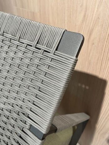 Nahaufnahme eines 2er-Sets Phoenix Outdoor-Sessel von Molteni&C, mit einer Stuhllehne mit dicht geflochtenen hellgrauen Schnüren und einem Hintergrund aus Holz oder Laminat.