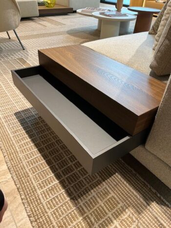 Ein moderner Beistelltisch aus Holz mit einer teilweise offenen Schublade ist an der Seite eines beigen Marteen-Sofas von Molteni&C befestigt, das auf einem strukturierten Teppich ruht.