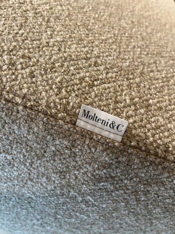 Nahaufnahme eines strukturierten beigen Stoffes des luxuriösen Marteen-Sofas mit einem kleinen eingenähten Etikett, das den Markennamen Molteni&C zeigt.
