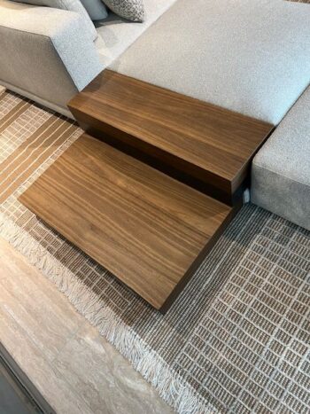 Ein zweistöckiger Beistelltisch aus Holz steht neben einem luxuriösen Molteni&C Marteen Sofa, das auf einem gemusterten Teppich mit Fransen steht.