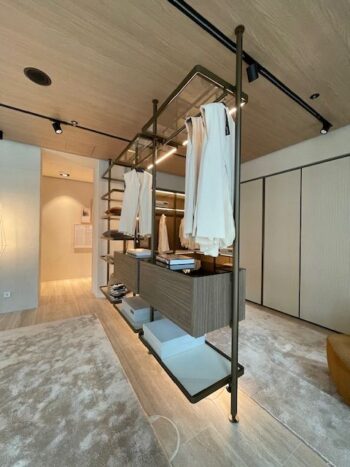 Moderner offener Kleiderschrank von Molteni&C mit Holzregalen, Hängekleidern, Schubladen und Aufbewahrungsboxen in einem minimalistischen, gut beleuchteten Ankleidezimmer mit hellen Wänden und Bodenbelägen.