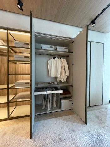 Ein moderner Kleiderschrank von Molteni&C aus der Kollektion Gliss Master Ankleide zeigt offene Türen mit ordentlich aufgehängten weißen Hemden, Regale mit Aufbewahrungsboxen und eine geordnete ausziehbare Schublade mit Fächern.