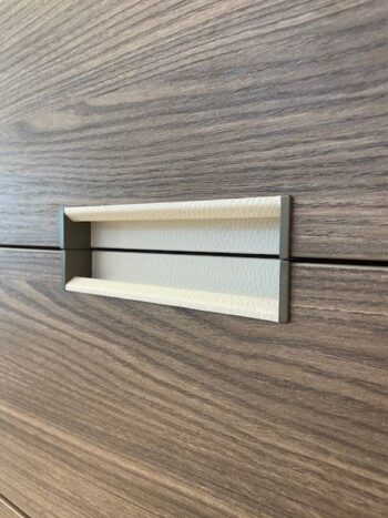 Nahaufnahme eines versenkten Griffs an einer holzverkleideten Schublade aus der Kollektion Gliss Master Ankleide von Molteni&C. Der Griff ist in die Oberfläche eingelassen und waagerecht ausgerichtet.