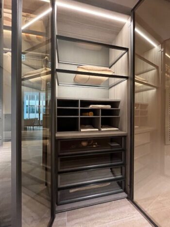 Moderner begehbarer Kleiderschrank mit Glastüren, offenen Einlegeböden und Fächern für gefaltete Kleidung und kleine Gegenstände, mit Akzenten aus Holz und Metall - eine elegante Lösung von Molteni&C Gliss Master Kleiderschrank.