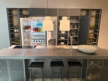 Molteni Abverkauf, Outlet, Angebot: Moderne Molteni&C-Küche mit einer Insel, drei Hockern, einem Mittelstück aus Stein, einem offenen Kühlschrank mit Getränken und offenen Schränken mit Geschirr und Weinflaschen. Die Ratio Essenza Küche ist elegant mit hochwertigen Küchengeräten ausgestattet.
