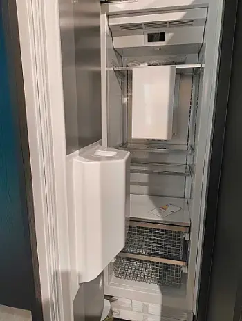 Molteni Abverkauf, Outlet, Angebot: Ein offener, leerer Kühlschrank mit mehreren Drahtablagen und einem eingebauten Eiswürfelbereiter in der Tür, perfekt für eine moderne Küche mit Geräten oder zur Ergänzung des eleganten Designs einer Ratio Essenza Küche von Molteni&C.