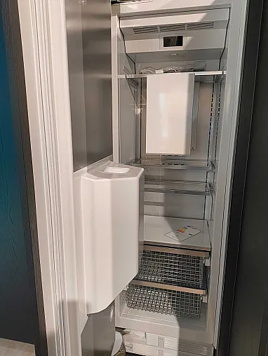 Ein offener, leerer Kühlschrank mit mehreren Drahtablagen und einem eingebauten Eiswürfelbereiter in der Tür, perfekt für eine moderne Küche mit Geräten oder zur Ergänzung des eleganten Designs einer Ratio Essenza Küche von Molteni&C.