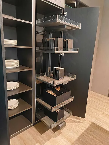 Ein hoher schwarzer Ratio Essenza-Küchenschrank mit mehreren ausziehbaren Fächern für Küchengeräte und Taschen; daneben befinden sich Regale von Molteni&C, in denen weiße Teller ordentlich gestapelt sind.