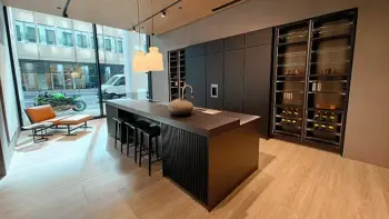 Molteni Abverkauf, Outlet, Angebot: Moderne Küche mit einer Molteni&C Ratio Essenza Küche, großer schwarzer Insel, eleganten Küchengeräten, Barhockern, eingebauten Regalen mit Weinflaschen, Sessel am Fenster und Blick auf die Straße.