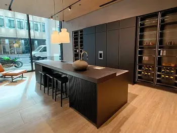 Molteni Abverkauf, Outlet, Angebot: Moderne Küche mit einer Molteni&C Ratio Essenza Küche, großer schwarzer Insel, eleganten Küchengeräten, Barhockern, eingebauten Regalen mit Weinflaschen, Sessel am Fenster und Blick auf die Straße.
