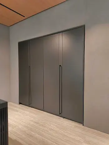 Molteni Abverkauf, Outlet, Angebot: Vier hohe, mattgraue Einbauschränke aus der Molteni&C Ratio Essenza Küche Kollektion sind mit vertikalen Griffen versehen und fügen sich nahtlos in eine glatte, hellgraue Wand über einem hellen Holzboden ein - ideal für die Unterbringung moderner Küchengeräte.