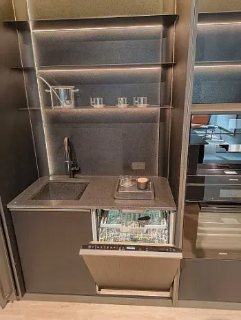 Molteni Abverkauf, Outlet, Angebot: Kompakte, moderne Ratio Essenza Küche mit einer kleinen Spüle, einem Induktionskochfeld, offenen Regalen und einem eingebauten Geschirrspüler mit geöffneter Tür, auf der sauberes Geschirr neben schlanken Küchengeräten zu sehen ist.