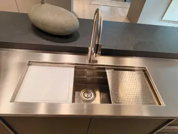 Molteni Abverkauf, Outlet, Angebot: Edelstahlspüle mit modernem Wasserhahn, integriertem Schneidebrett, Sieb und einem dekorativen Steinobjekt auf der Arbeitsplatte - die perfekte Ergänzung für Ihre Molteni&C Ratio Essenza Küche und Premium Küchengeräte.