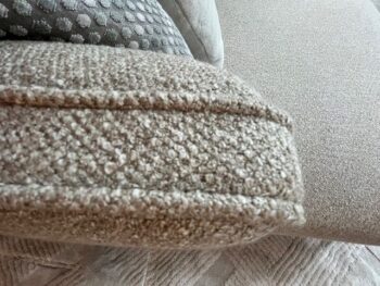 Nahaufnahme eines strukturierten beigen Molteni&C Paul Sofa-Kissens mit einem gemusterten Kissen und einer glatten Sitzfläche im Hintergrund.