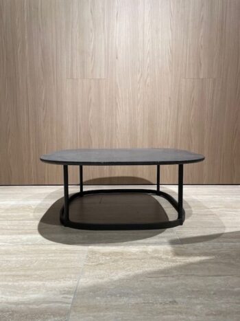 Ein schwarzer, rechteckiger Regent Beistelltisch mit abgerundeten Kanten und einem Metallfuß steht auf einem gefliesten Boden vor einer holzgetäfelten Wand und zeigt das zeitlose Design von Molteni&C.