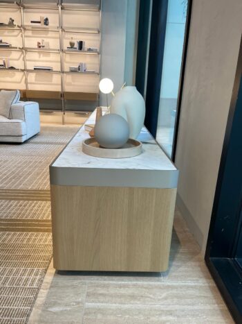 Ein modernes Molteni&C Living Box Sideboard mit einer Marmorplatte zeigt minimalistische Keramikvasen und eine Lampe; im Hintergrund sind Regale und ein Sofa zu sehen.