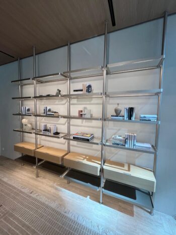 Das moderne Regal Molteni&C aus Metall und Holz, Teil des Hector Regalsystems, steht an einer Wand und präsentiert verschiedene Bücher, Dekorationsgegenstände und Vasen in einer minimalistischen Anordnung.