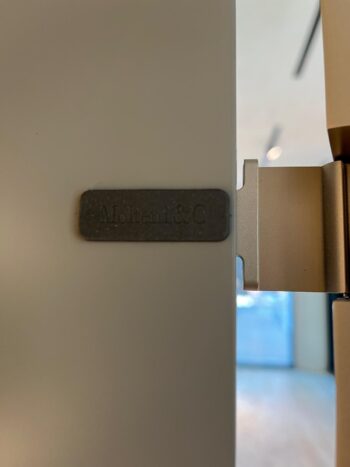 Nahaufnahme eines Türscharniers mit einem seitlich angebrachten Metallschild mit der Aufschrift Molteni&C, das die Handwerkskunst von Molteni-Möbeln und -Designs wie dem 505 UP System zeigt.