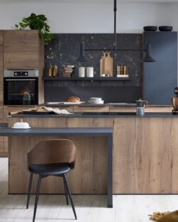 Moderne Küche mit Holzschränken, schwarzen Arbeitsplatten, offenen Regalen, zwei Stühlen an einer Insel und verschiedenen Küchengeräten und Dekorationsartikeln in geordneter Anordnung.