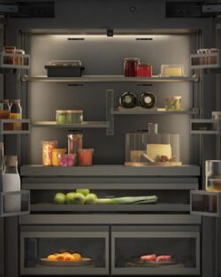Ein offener Kühlschrank mit ordentlich angeordneten Flaschen, Gläsern, Obst, Gemüse, Eiern und Getränken auf Regalen und in Schubladen.