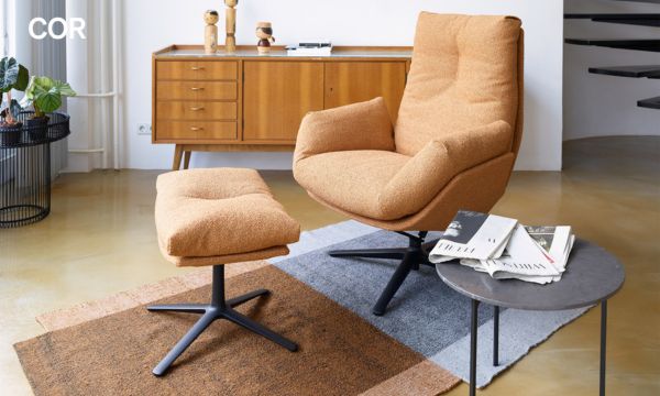 Ein modernes Wohnzimmer vom Möbelhaus Bad Homburg besteht aus einem hellbraunen Loungesessel mit passender Ottomane, einem runden Beistelltisch mit Zeitschriften, einem gemütlichen Teppich, einem hölzernen Sideboard und stilvollen Dekorationsartikeln. Ein modernes Wohnzimmer vom Möbelhaus Bad Homburg besteht aus einem hellbraunen Loungesessel mit passender Ottomane, einem runden Beistelltisch mit Zeitschriften, einem gemütlichen Teppich, einem hölzernen Sideboard und stilvollen Dekorationsartikeln.