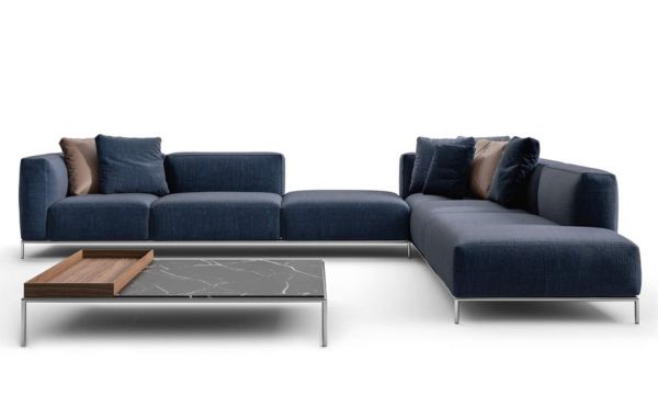 Ein modernes dunkelblaues Sektionssofa mit braunen und blauen Kissen vom Möbelhaus Bad Homburg steht neben einem rechteckigen Couchtisch mit einer Oberfläche aus Marmor und Holz.