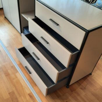 Ein Sideboard mit vier Schubladen, bei dem alle Schubladen teilweise geöffnet sind, steht auf einem Holzboden - ein elegantes Möbelstück von Dauphin Home.