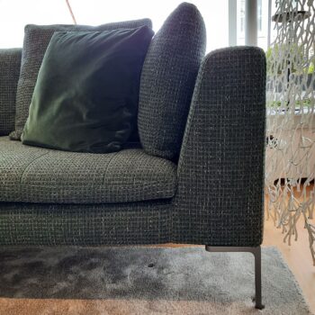 Nahaufnahme eines modernen, dunkelgrünen B&B Italia Charles Sofas mit passendem Kissen, Metallbeinen, auf einem grauen Teppich in einem gut beleuchteten Raum.