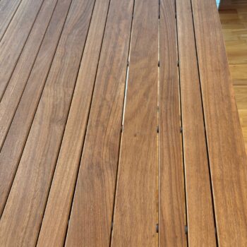Nahaufnahme einer Teakholzoberfläche des B&B Italia Mirto Outdoortischs mit gleichmäßig verteilten, parallelen Planken und sichtbarer Holzmaserung.