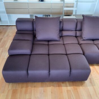 Ein modernes Tufty-Time-Sofa von B&B Italia mit dunkelvioletter Polsterung und quadratischen Tufting-Kissen steht stilvoll auf einem Holzboden in einem zeitgenössischen Wohnzimmer.