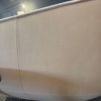 Nahaufnahme der Rückseite eines beige gepolsterten COR NOOK Sofas mit strukturiertem Stoffrand und einer grauen Wand im Hintergrund.