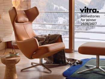 Ein Ledersessel mit einer Decke, einem passenden Hocker und einem Beistelltisch steht vor einem Fenster mit Blick auf schneebedeckte Berge. Diese einladende Einrichtung, die gutes Design verkörpert, ist Teil der Kollektion „Vitra Home Stories for Winter 2026/2027“. Ein Schriftzug mit der Aufschrift „Homestories für den Winter 2026/2027“ rundet das Bild ab.
