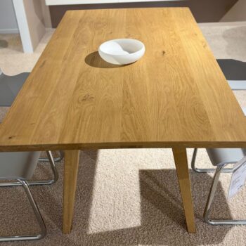 Ein Dolomit Esstisch - ein rechteckiger Holztisch mit vier Metallstühlen und einer weißen Schale in der Mitte - steht elegant auf einem beigen Teppich.