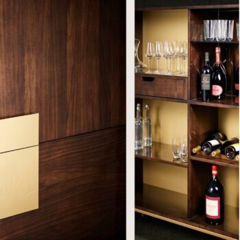 Barschrank im Brooklyn-Stil aus dunklem Holz mit goldfarbenen Akzenten, mit offenen Regalen, in denen Weinflaschen, Gläser und Dekanter untergebracht sind.