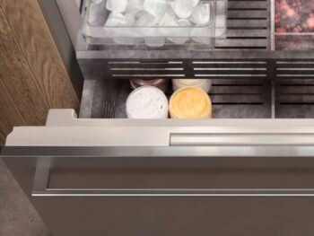Gaggenau 400 Vario Serie: Öffnen Sie die Gefrierschublade des Gaggenau 400, in der sich eine Schale mit Eiswürfeln, ein Teil mit gefrorenen Beeren und mehrere Behälter mit Eis oder gefrorenen Desserts befinden.