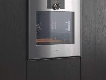 Gaggenau Expressive: Ein Gaggenau-Edelstahl-Einbaubackofen der Expressive Serie mit Digitalanzeige und Bedienknopf ist in einen dunklen Holzschrank eingelassen.