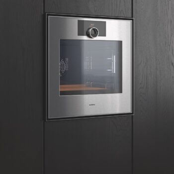 Gaggenau Expressive: Ein Gaggenau-Edelstahl-Einbaubackofen der Expressive Serie mit Digitalanzeige und Bedienknopf ist in einen dunklen Holzschrank eingelassen.