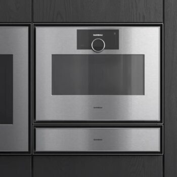 Gaggenau Expressive: Ein Einbau-Mikrowellenherd aus Edelstahl von Gaggenau aus der Expressive Serie mit Digitalanzeige und Bedienknopf in einem dunklen Schrank.