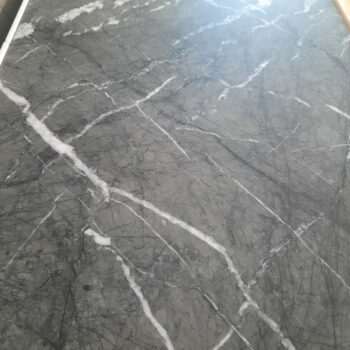 Eine Nahaufnahme einer grauen Marmor-Arbeitsplatte mit weißen und dunklen Maserungen, die sich über die Oberfläche ziehen, in Kombination mit einem Sideboard von Interlübke.