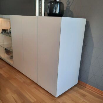 Ein modernes Sideboard von Interlübke steht auf einem Holzfußboden, auf dem eine schwarze Vase steht und auf der linken Seite Glasböden zu sehen sind.