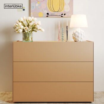 Eine beigefarbene Interlübke-Kommode mit drei Schubladen und einer Vase mit weißen Tulpen, zwei Kerzenständern und einer Lampe. An der Wand darüber hängt abstrakte Kunst, die Ihr modernes Sideboard in Schwung bringt.