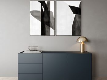 Minimalistisches Zimmer mit einem Interlübke-Sideboard in Dunkelblau, einer Glasschale, einer goldenen Lampe und zwei abstrakten Schwarz-Weiß-Bildern an einer grauen Wand. Das Interlübke-Logo in der oberen linken Ecke ist der perfekte Start in ein raffiniertes Leben.