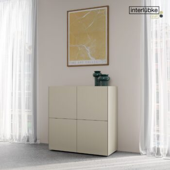 Ein minimalistisches beigefarbenes Interlübke-Sideboard steht vor einer hellen Wand, darüber ein gerahmtes abstraktes Kunstwerk und zwei grüne Vasen. Weiße Vorhänge verdecken große Fenster im Hintergrund.