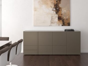 Ein minimalistischer Raum mit einem taupefarbenen Interlübke-Sideboard, drei weißen und braunen Stühlen, dunklem Holzfußboden, einer Würfelleuchte und einem abstrakten Gemälde, das an der weißen Wand über dem Sideboard hängt.