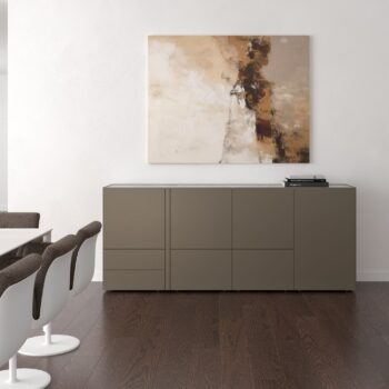 Ein minimalistischer Raum mit einem taupefarbenen Interlübke-Sideboard, drei weißen und braunen Stühlen, dunklem Holzfußboden, einer Würfelleuchte und einem abstrakten Gemälde, das an der weißen Wand über dem Sideboard hängt.
