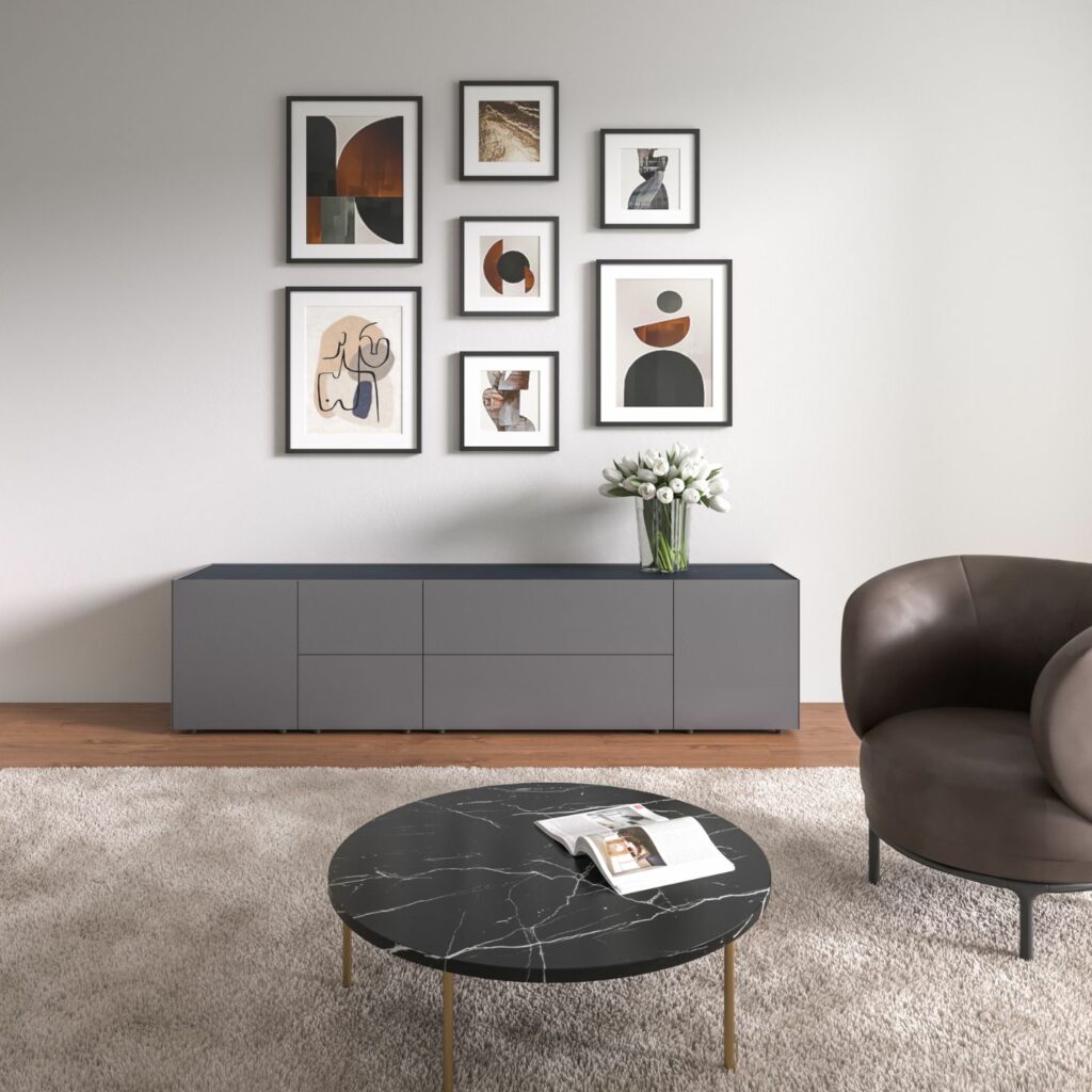 Modernes Wohnzimmer mit einem Interlübke-Sideboard, einer Wand mit abstrakter Kunst, einem runden Couchtisch aus schwarzem Marmor, einem Sessel und einer Vase mit weißen Blumen, die von einer eleganten Würfelleuchte beleuchtet wird.