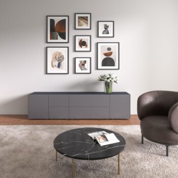 Modernes Wohnzimmer mit einem Interlübke-Sideboard, einer Wand mit abstrakter Kunst, einem runden Couchtisch aus schwarzem Marmor, einem Sessel und einer Vase mit weißen Blumen, die von einer eleganten Würfelleuchte beleuchtet wird.